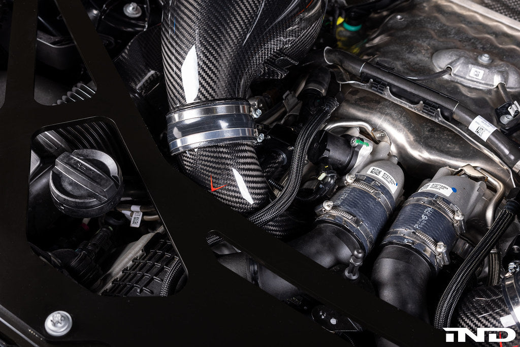 Close-up view of a BMW engine bay showing an LCI model S68 engine with carbon fiber turbo inlets for BMW LCI S68 with CNC machined flanges, branded with 'Eventuri' logo, against a white background.
