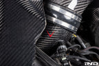 Close-up of the Eventuri F9X X5M X6M G09 XM M60i LCI carbon turbo inlet set installed on a BMW engine for performance enhancement.