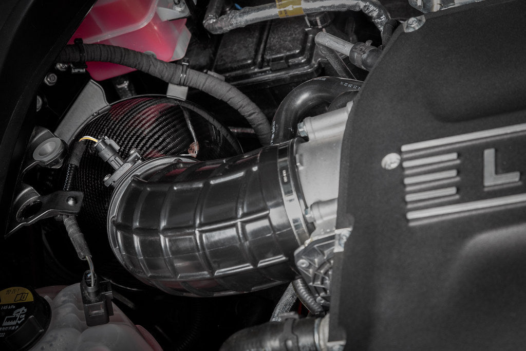 Eventuri Lotus Emira V6 black carbon intake system installed, showcasing its sleek design and performance-focused construction.