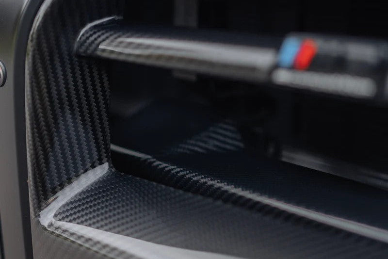TREVORA G8X M3 M4 pre-preg carbon fiber foam crash bar cover on exterior of vehicle, showcasing sleek dark carbon fiber finish.