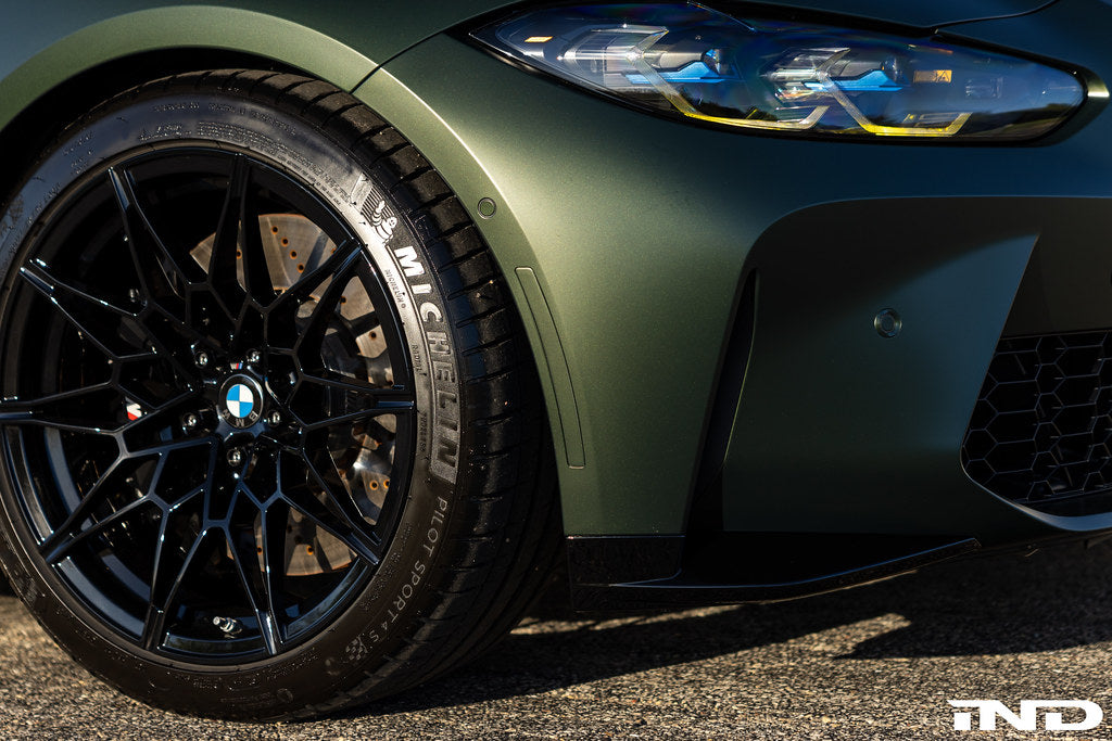 G82 BMW M4 with IND painted front reflectors installed, front three-quarter view showing body-color matched reflector upgrade on factory front bumper