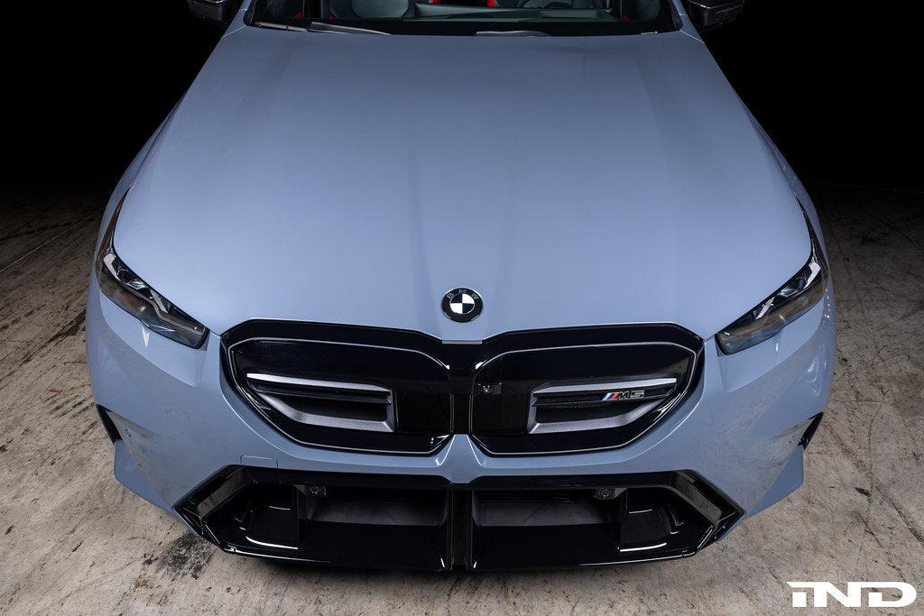 IND Carbon BMW Roundel Set installed on a BMW showing hand-laid carbon fiber details, gloss black surrounds, and OEM fitment appearance