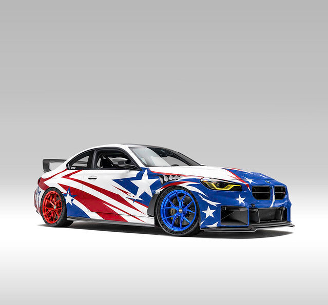 BMW G87 M2 featuring patriotic red, white, and blue 4th of July livery promoting the IND Distribution USA26 sitewide Independence Day sale