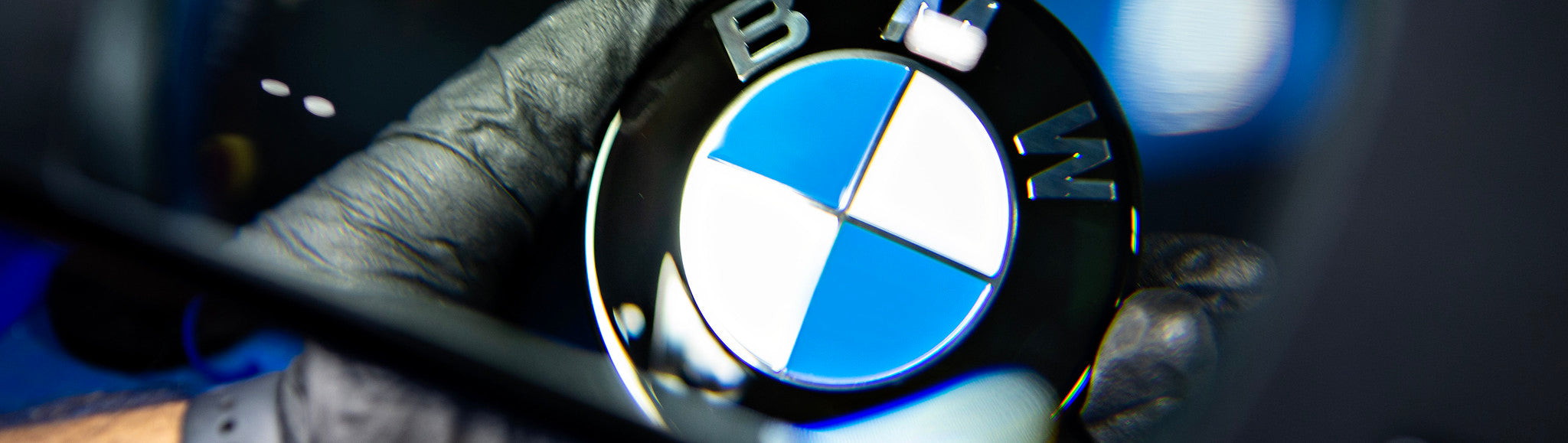 IND Technician Performing Final Quality Control Inspection on Painted BMW Roundel Using Magnifying Glass Prior to Shipment