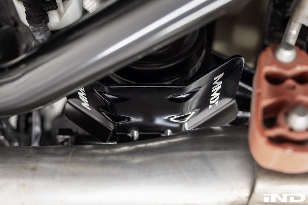 MMX Performance heat shield installed on a BMW G8X rear differential, black anodized face visible above the exhaust pipe