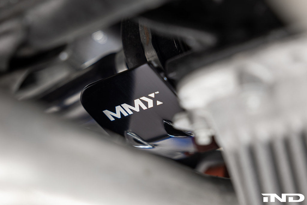 Close-up of an MMX Performance heat shield fitted beside the BMW G8X differential, with the MMX logo on the black anodized face