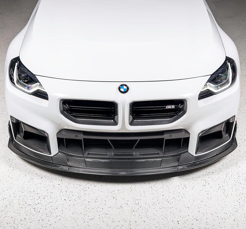 TREVORA TR87 Track pre-preg carbon fibre front splitter installed on Alpine White BMW G87 M2 front view showcasing the aggressive twin-level splitter design