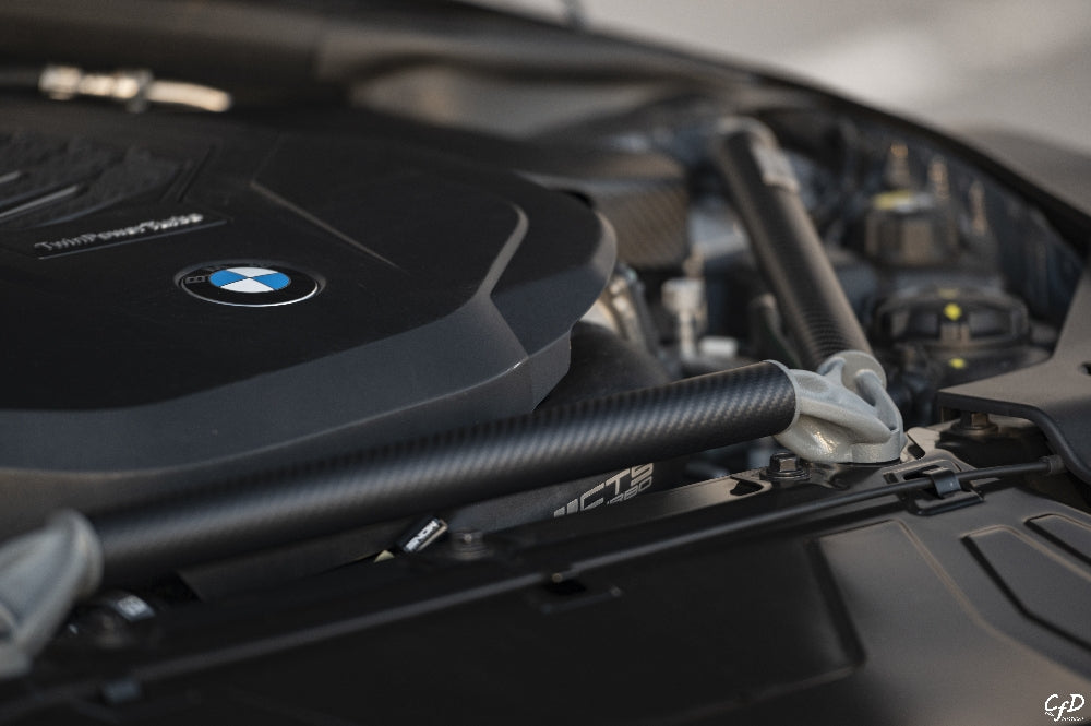 AptusWorks ACX A90 A91 MKV Supra DMLS carbon strut brace installed in engine bay for enhanced suspension stability.