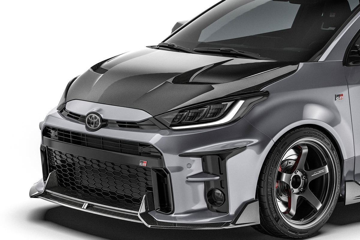 ADRO Toyota GR Yaris with prepreg carbon fiber hood installed, shown from an angled exterior view highlighting the lightweight, glossy finish