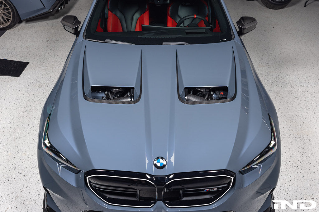 Alpha N BMW G90 G99 M5 carbon vented hood installed on exterior of vehicle, showcasing lightweight design and venting features.