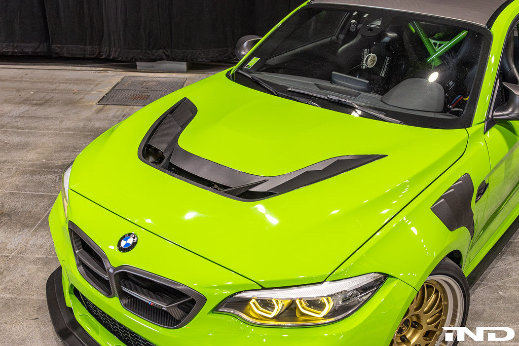 Alpha N F87 M2 Carbon Corse vented hood installed on a car, showcasing its lightweight, aerodynamic design and carbon fiber finish.