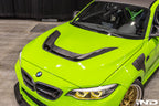 Alpha N F87 M2 Carbon Corse vented hood installed on a car, showcasing its lightweight, aerodynamic design and carbon fiber finish.