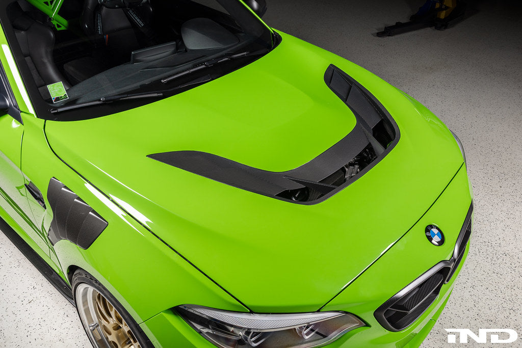 Alpha N F87 M2 Carbon Corse vented hood installed, showing its lightweight carbon fiber design and aerodynamic vents.
