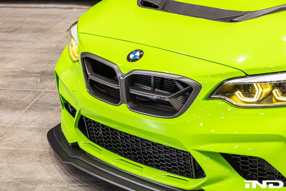Alpha N F87 M2 Competition CS Carbon Corse front grille installed on BMW M2, showcasing sleek exterior design and carbon fiber detail.