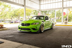 Alpha N F87 M2 Competition CS Carbon Corse front splitter installed on a BMW M2, showcasing its aerodynamic exterior design.