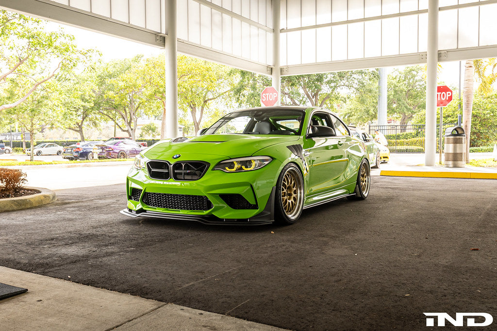 Alpha N F87 M2 Competition CS Carbon Corse front splitter installed on a BMW M2, showcasing its aerodynamic exterior design.