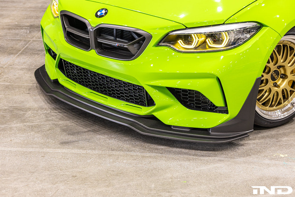 Alpha N F87 M2 Competition CS Carbon Corse front splitter installed on the exterior of a BMW M2, showcasing its aerodynamic design.