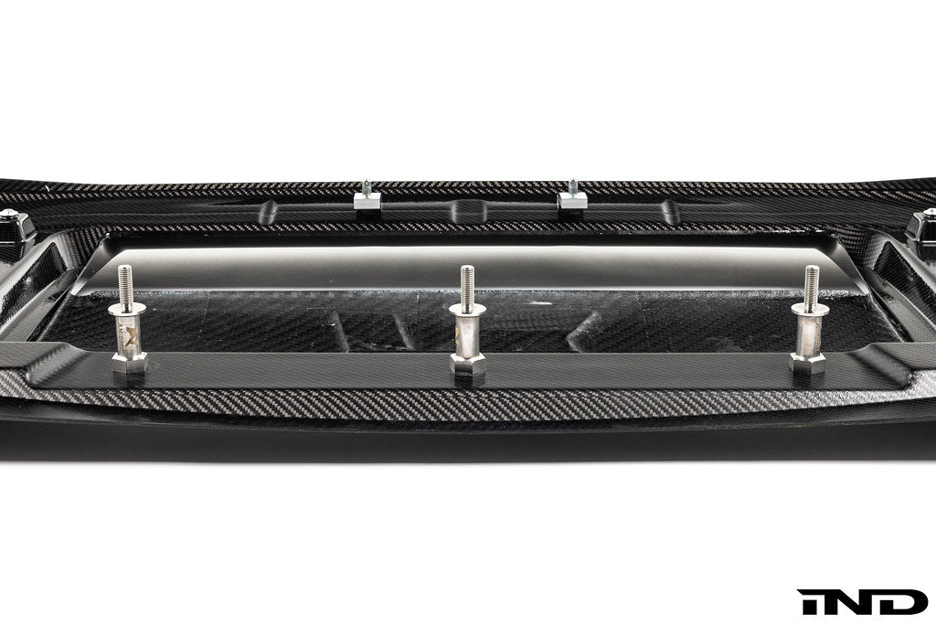 Alpha N G87 M2 Carbon Corse front splitter mounted on a car, showcasing its sleek white carbon fiber design and aerodynamic features.