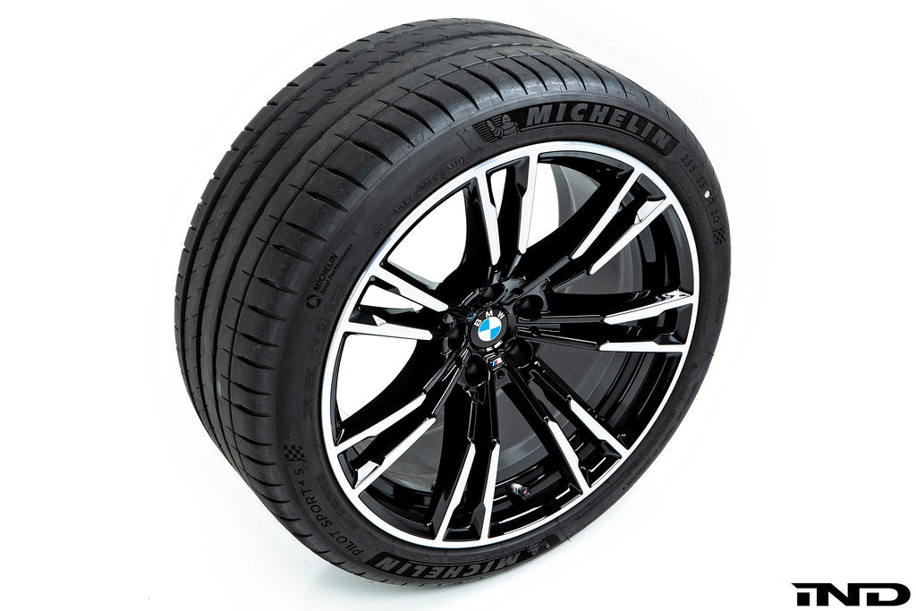 IND Gloss Black Wheel Center Cap Set for BMW, 56mm, installed on wheel with tire, against a white background.