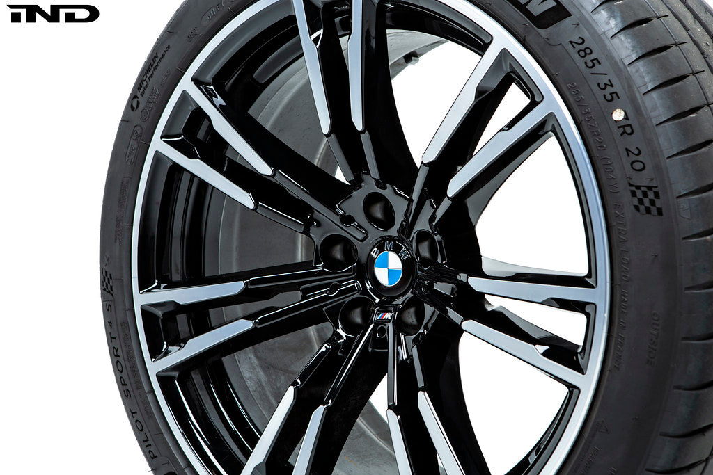 IND Gloss Black Wheel Center Cap Set for BMW, 56mm, installed on wheel with tire, on white background.