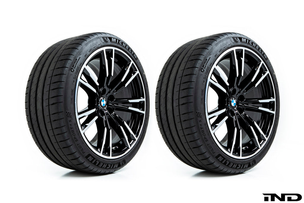 BMW wheels with 56mm center caps installed showing IND gloss black center cap compared to factory chrome center cap on white background