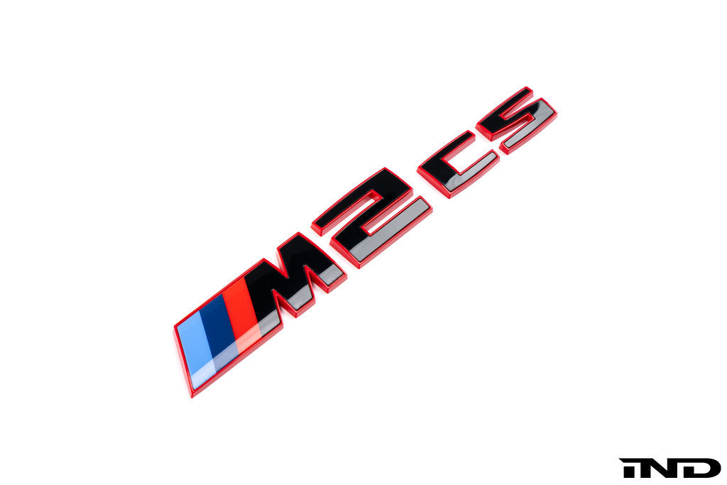 BMW G87 M2 CS trunk emblem in gloss black with red border on white background, exterior car badge.