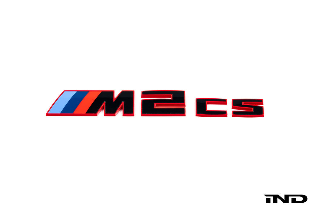 BMW G87 M2 CS trunk emblem in gloss black with red border on a white background, exterior car accessory.