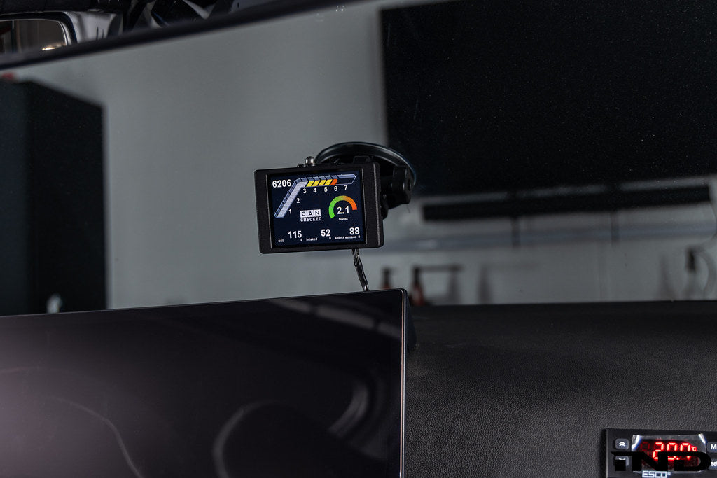 CANchecked MFD32 Gen2 3.2-inch multi-function display installed in BMW G87 M2 interior, showing digital gauges and controls.