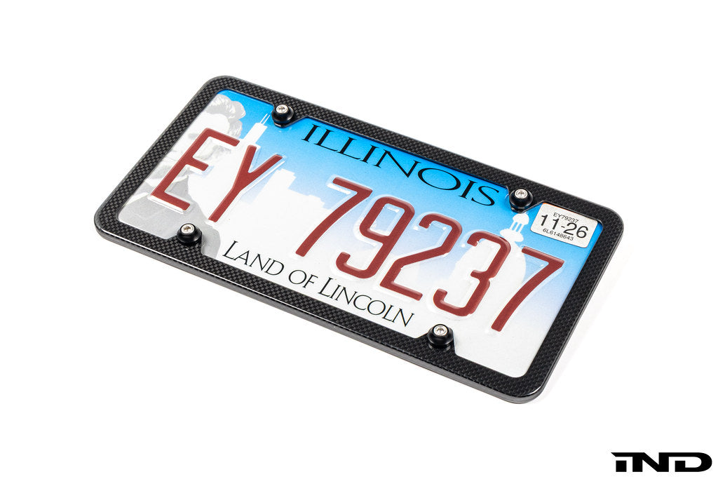 Downstar BMW License Plate Dress Up Hardware installed on a license plate with a carbon fiber license plate frame, featuring stainless steel fasteners and billet aluminum beauty washers, shown on a white background.
