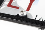 Downstar BMW License Plate Dress Up Hardware installed on a license plate with a carbon fiber license plate frame, featuring stainless steel fasteners and billet aluminum beauty washers, shown on a white background.