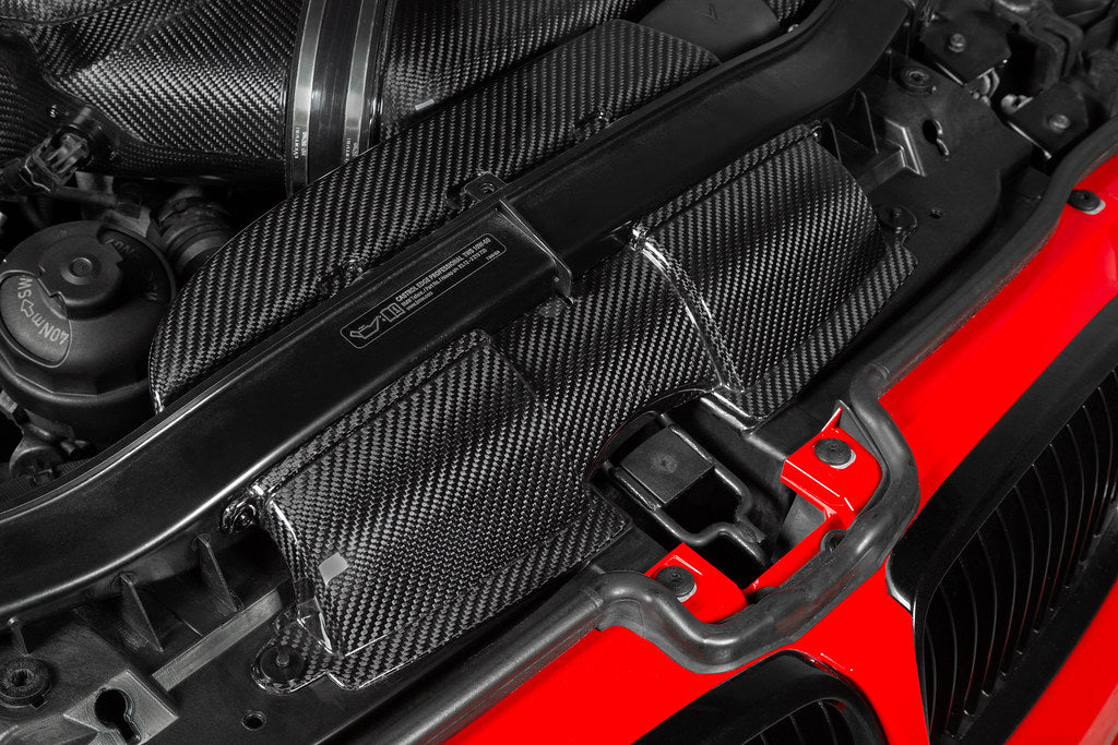 Eventuri gloss carbon fiber duct set installed in the engine bay of a red BMW E92 M3 Coupe