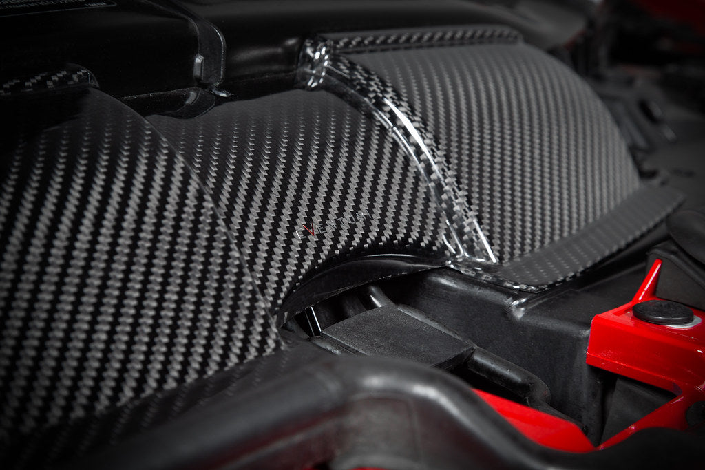 Eventuri gloss carbon fiber duct set installed in the engine bay of a red BMW E92 M3 Coupe