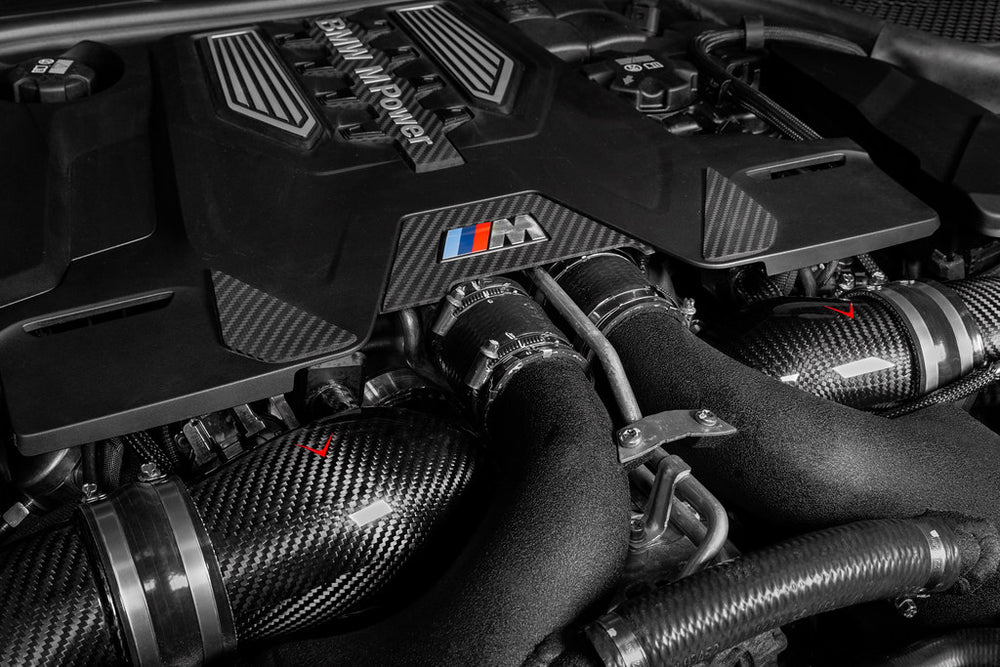 Installed Eventuri carbon turbo inlets on a BMW F90 M5 showing the optimized airflow path and pre-preg carbon fiber construction.