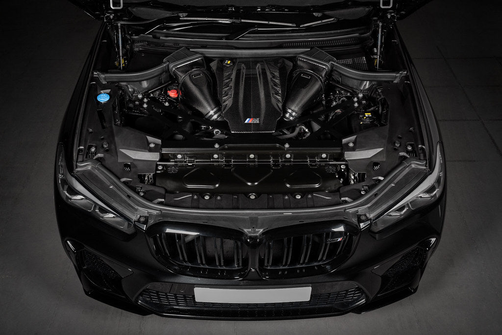 Eventuri black carbon performance intake system installed in BMW F95 X5M engine bay, enhancing airflow and engine performance.