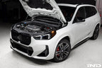 Eventuri black carbon intake system installed on BMW X1 M35i with Alpine White, showcasing performance upgrade details.