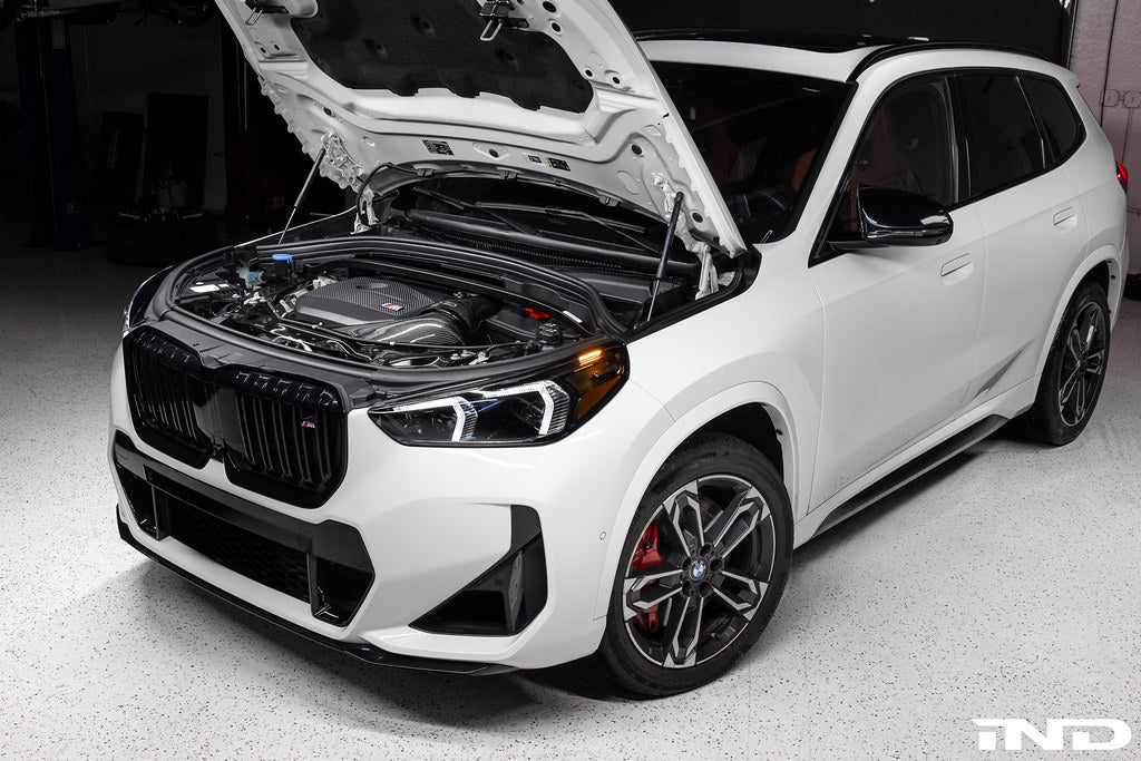 Eventuri black carbon intake system installed on BMW X1 M35i with Alpine White, showcasing performance upgrade details.