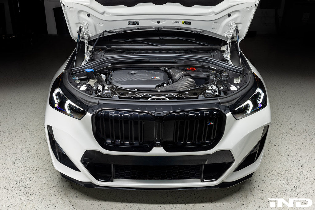 Eventuri black carbon intake system installed in a BMW X1 M35i, showcasing performance upgrade on a white vehicle.