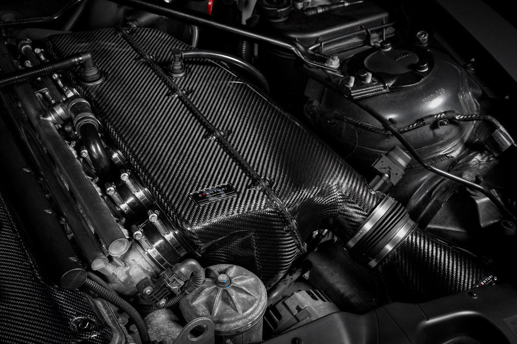Eventuri hybrid carbon airbox system installed in BMW Z4 M engine bay, showcasing sleek carbon fiber design and performance components.
