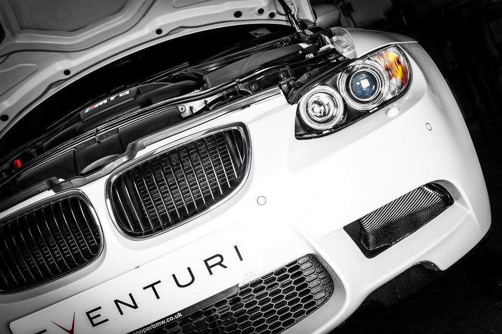 Eventuri black carbon intake system installed in engine bay of BMW E9X M3 (S65) performance vehicle, showcasing glossy finish.