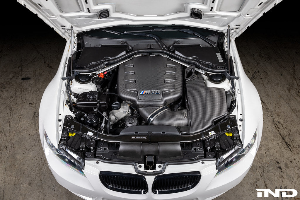 Overhead installed view of Eventuri E9X M3 S65 matte black carbon airbox lid with optional intake and plenum in engine bay

