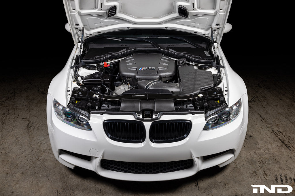 Overhead installed view of Eventuri E9X M3 S65 matte black carbon airbox lid with optional intake and plenum in engine bay
