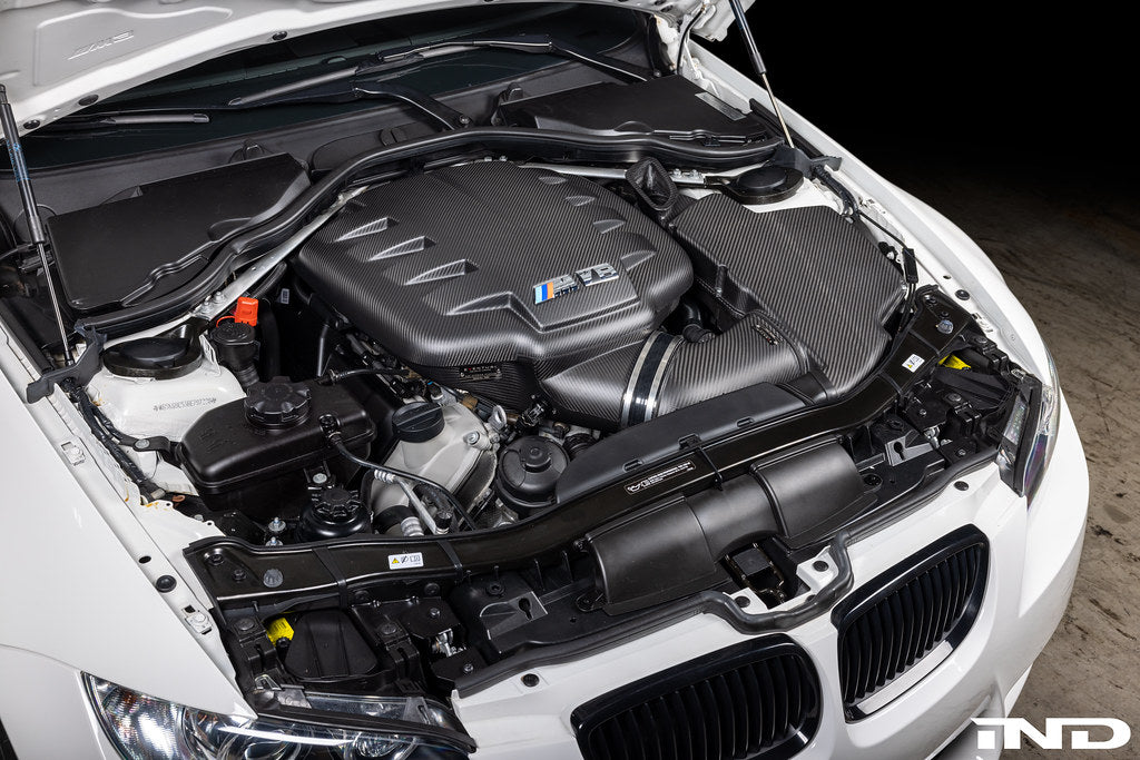 Overhead installed view of Eventuri E9X M3 S65 matte black carbon airbox lid with optional intake and plenum in engine bay
