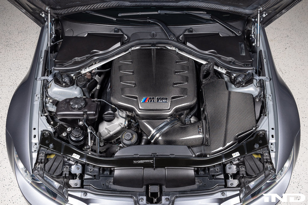 Eventuri black carbon inlet plenum installed in BMW E9X M3 engine bay, showcasing gloss finish and performance enhancement.