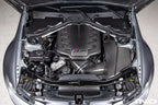 Eventuri black carbon inlet plenum installed in BMW E9X M3 engine bay, showcasing gloss finish and performance enhancement.