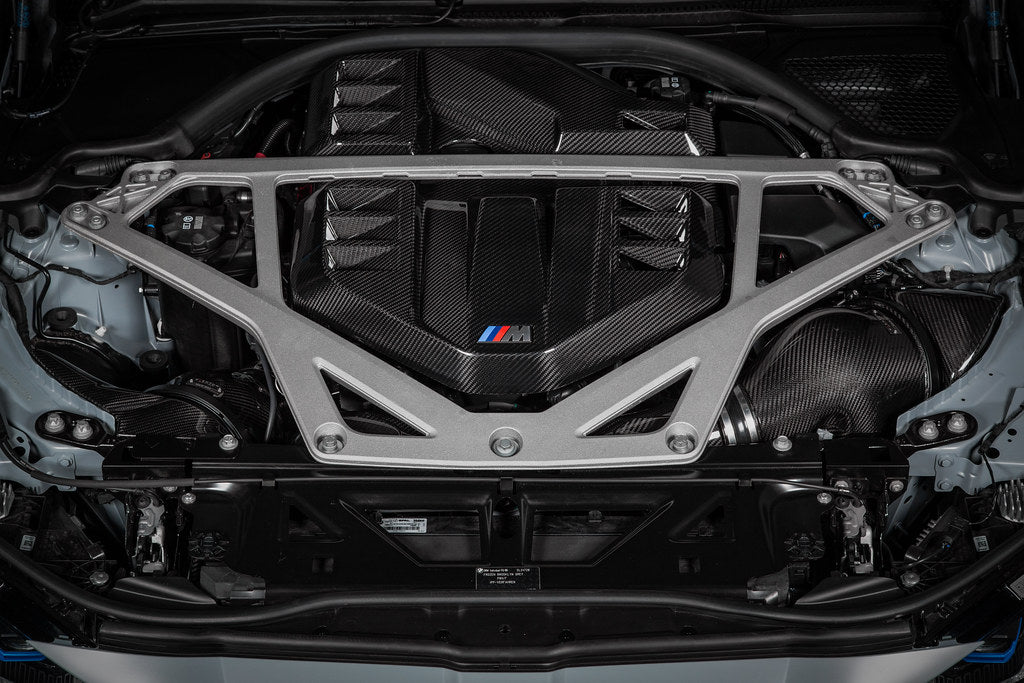 Eventuri black carbon engine cover installed on BMW G8X M2, M3, M4 S58 engine bay, showcasing sleek exterior engine bay enhancement.