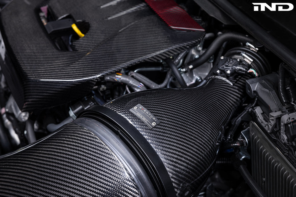 Eventuri GR Corolla carbon intake system installed in engine bay, showcasing glossy carbon fiber finish for enhanced performance.