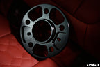 Black FC 5x112 BMW wheel spacer displayed on red interior seat showing anodized finish and precision machining