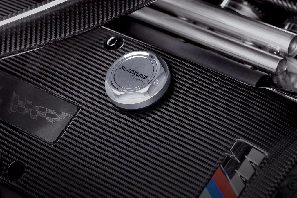 Goldenwrench BMW M Blackline Oil Cap Heritage Motorsport installed on engine exterior, featuring sleek black design and branding.
