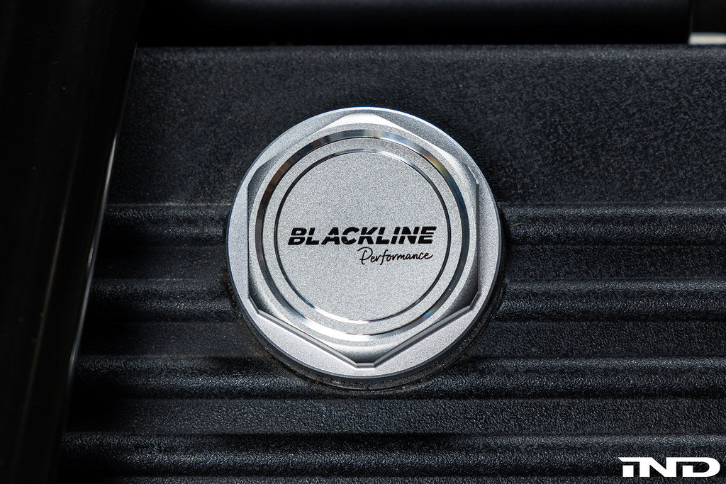 Goldenwrench BMW M Blackline Heritage Motorsport oil cap installed on the engine exterior, showcasing sleek black design.