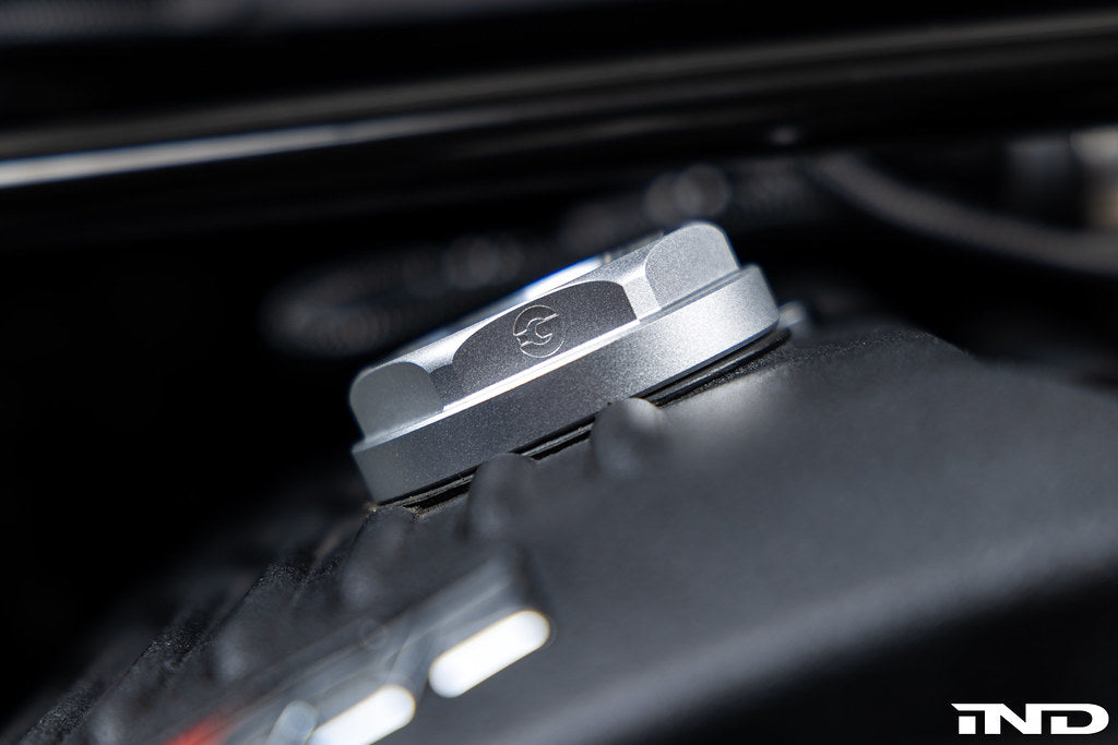 Goldenwrench BMW M Blackline Oil Cap Heritage Motorsport installed on car exterior, showcasing sleek black design and branding.
